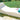 White Surf sun lounge with a pillow and a rolled turquoise towel on a stone patio beside a lawn
