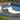 White Surf sun lounge with a headrest pillow beside an infinity pool and a round ottoman