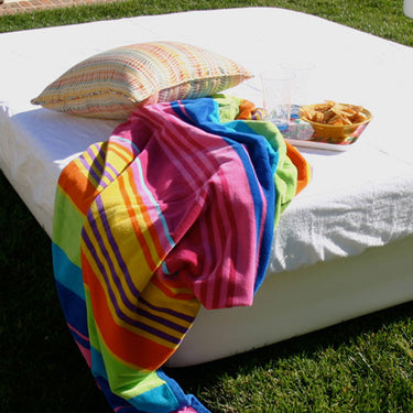 Striped terrycloth topper draped over a white Crib Queen resort bed on the lawn