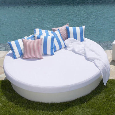 White Sun Pad round daybed by a pool with blue and white striped pillows