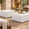 Two Zinc square ottomans in white vinyl on a woven rug at the edge of a spa pool