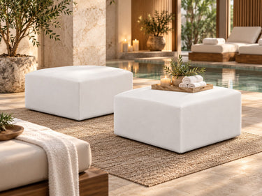 Two Zinc square ottomans in white vinyl on a woven rug at the edge of a spa pool