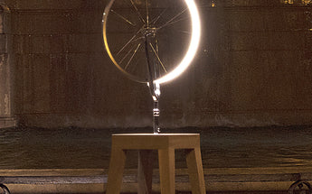 Marcel by Cyclampa glowing at night, a ring of light on an oak stool