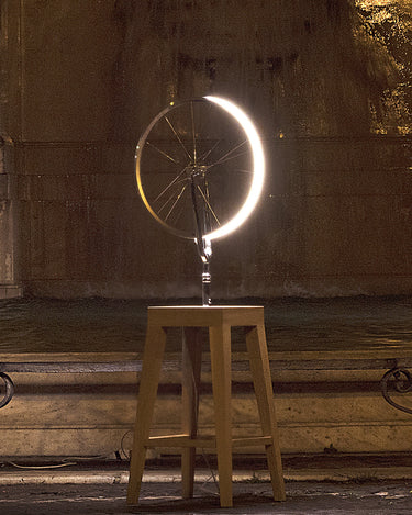 Marcel by Cyclampa glowing at night, a ring of light on an oak stool