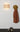 Skew 15 Blonde cardboard sconce lit on a wall, warm filtered glow