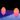 Two Smart & Green Rocky lamps glowing orange and pink above their violet reflection on the water