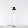 Modern LED floor lamp - Artemide La Petite - casting soft, ambient light in a bedroom, Black finish