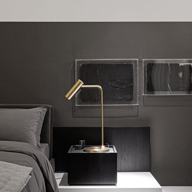 Heron table lamp with a slim stem and a cylindrical shade, in a room setting