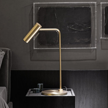 Heron table lamp with a slim stem and a cylindrical shade, in a room setting