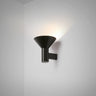 Torres wall light in bronze with a funnelled metal shade angled upward on a grey studio wall