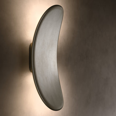 Penta Vela wall sconce in a second finish, lit on a wall