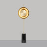 Pendulum floor lamp in satin brass with a smoked glass shade on a black marble base, studio view