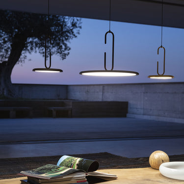Penta Clip pendants lit at dusk over a low table in a living space with large windows