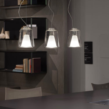 Three Oluce Lanternina pendant lights hanging over a dark kitchen counter