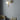 Big Bulb wall light in polished brass with a lit opal globe on a blue-grey wall above a green armchair and a brass table