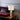Ring table lamp in satin brass on a wood side table beside a red velvet sofa