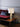 Ring table lamp in satin brass on a wood side table beside a red velvet sofa