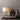 Close view of the Braque lamp with its cast base on a dark console beside a framed artwork