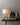 Close view of the Braque lamp with its cast base on a dark console beside a framed artwork
