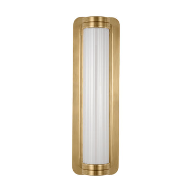 Dimmable Alo Small wall sconce in polished brass, installed horizontally next to a bed in a minimalist hotel room.