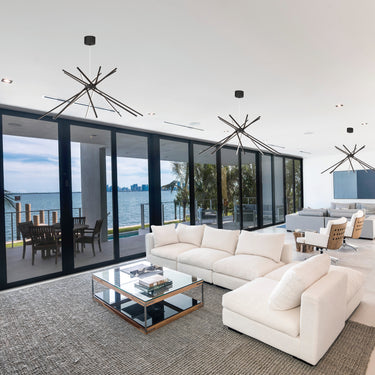ET2 Alumilux Aster starburst pendants above a white sectional in an open living room with glass walls