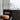 White Zanuso table lamp on a dark sideboard beside a leather stool