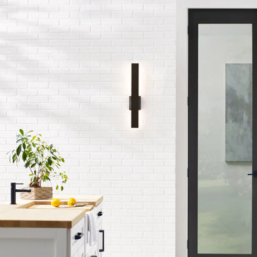 Blade 24 inch modern outdoor LED wall sconce, black finish, illuminating a brick wall. 