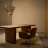 Shard pendant with bronze kiln glass panels above a wooden desk and a brown swivel chair