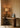 Roc table lamp glowing in a corner on a timber desk beside framed abstract art and a bentwood chair