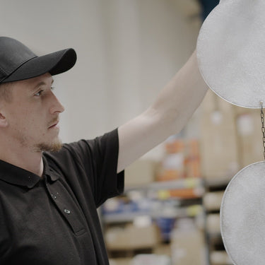 CTO Lighting team member hanging handmade glass discs for inspection in the workshop