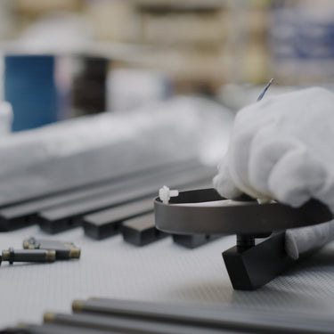 Gloved hands assembling a bronze fixture arm at a CTO Lighting workbench