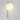 Tall Gaia wall light in satin brass with a lit shiny opal glass globe, shade facing up