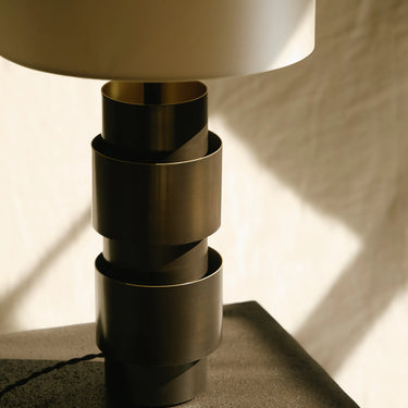 Close-up of the stacked bronze rings of the Ring table lamp beneath a silk shade