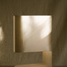 Columbo alabaster table lamp with a curved shade on a plinth against a draped backdrop