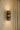 Ring wall light lit on a pale plaster wall beside a curtain