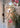 Lyndon outdoor wall lamp by Oluce mounted near flowering plants, lifestyle view