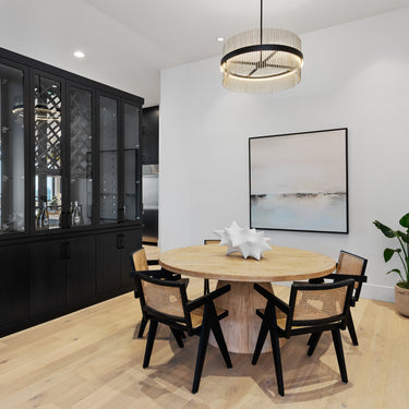 ET2 Chimes tube-ring pendant in Black and Satin Nickel over a round dining table with rattan chairs in front of a black glass-front cabinet