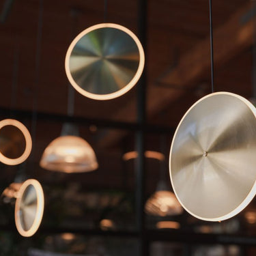 Cluster installation of mixed-size Graypants Chrona vertical brass disc pendants.