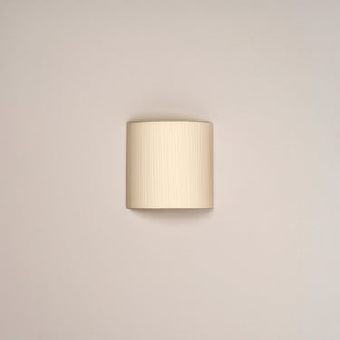 Minimalist natural ribbon wall lamp with warm ambient lighting by Santa and Cole