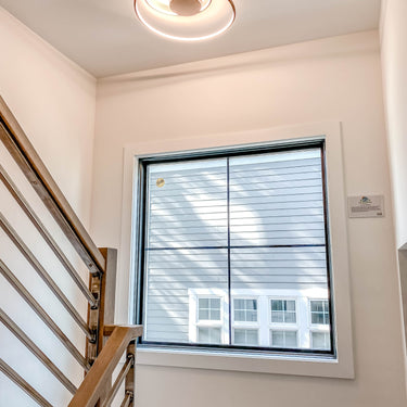 ET2 Cycle flush mount on the ceiling of a stairwell landing beside a window and wood handrail
