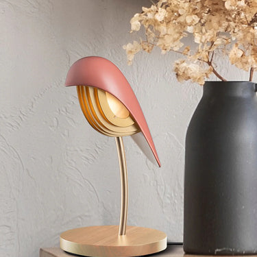 Warm light emitted from the Daqiconcept Bird LED Dimmable Table Lamp - Burnt Brick BR01BBL in a cozy living room