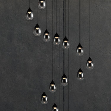 ET2 Dewdrop pendant drops of smoke-gradient glass hanging in a long cascade against a dark gray wall