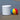 White La Fête Dot cylinder ottoman on wet sand beside a colorful beach ball