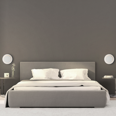 ET2 Revolver rotating halo wall sconce, two round white discs mounted either side of a bed on a dark gray bedroom wall