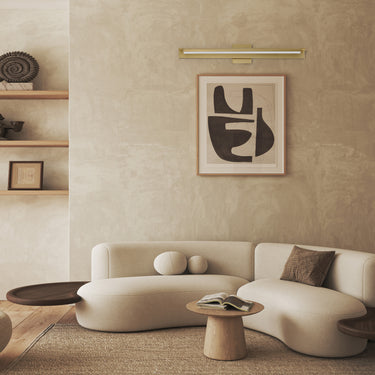 ET2 Bookkeeper picture light in Natural Aged Brass over framed art in a neutral living room