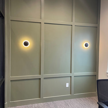 ET2 Saucer gold disc wall sconce, two glowing discs on a green paneled office wall