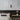 ET2 Handler mini spot light on a gray paneled bedroom wall above a bed with a dark headboard