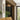 ET2 Loop looped tube wall sconce, Gold, mounted vertically on a stone wall beside a walnut-paneled entry in a living room