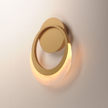 ET2 Lyra gold ring wall sconce lit, seen from the side on a cream wall