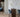 ET2 Manta curled acrylic wall sconces glowing on a marble wall beside a wood bar counter with blue stools